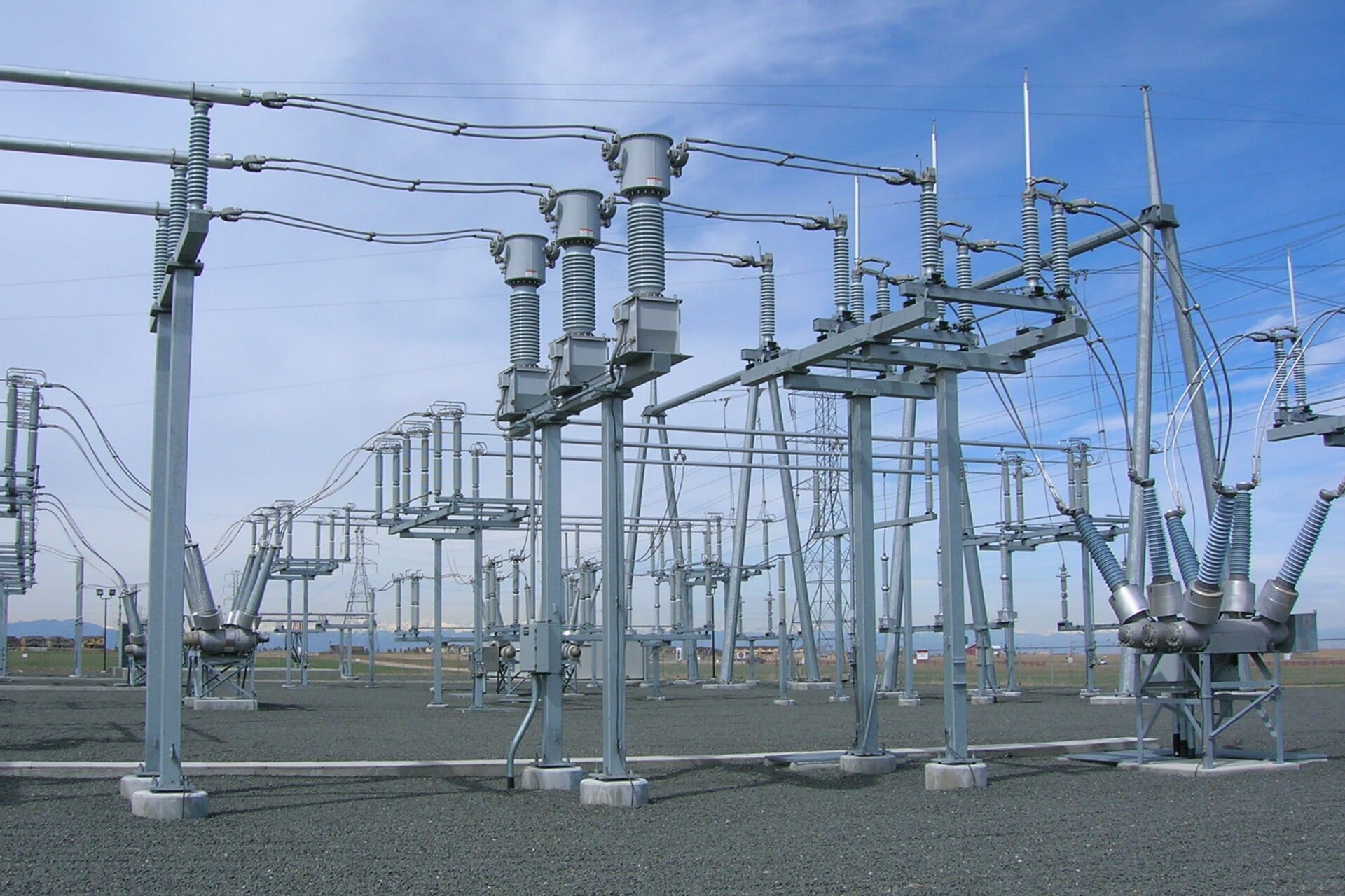 Tubular busbars, current transformers and disconnectors in an outdoor substation yard under a blue sky.